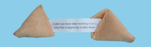 A person holding onto a fortune cookie with a quote.