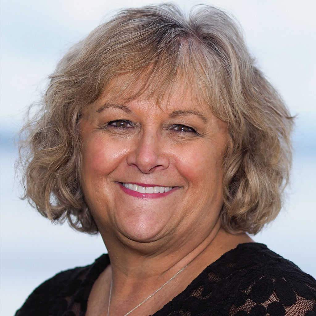 A woman with blonde hair and wearing black is smiling.