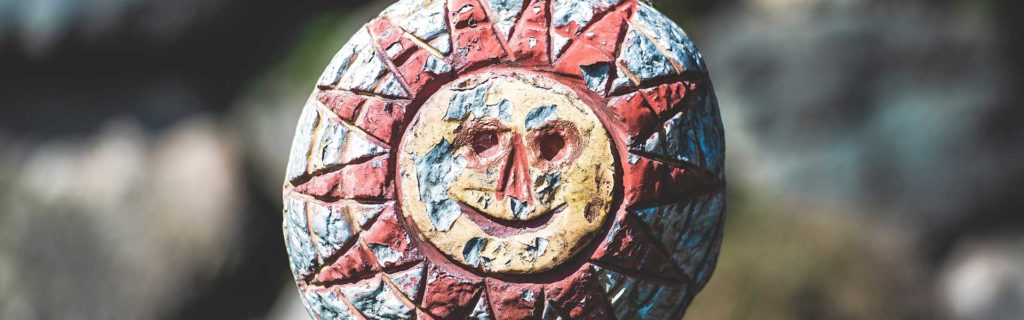 A sun face painted on the side of a rock.