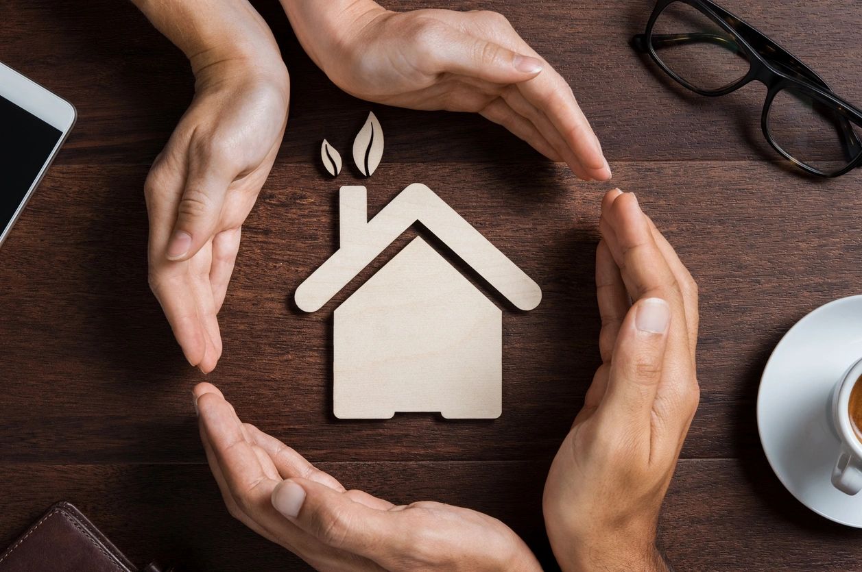 A group of people holding hands around a house.