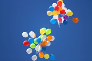 Two balloons are flying in the air on a clear day.